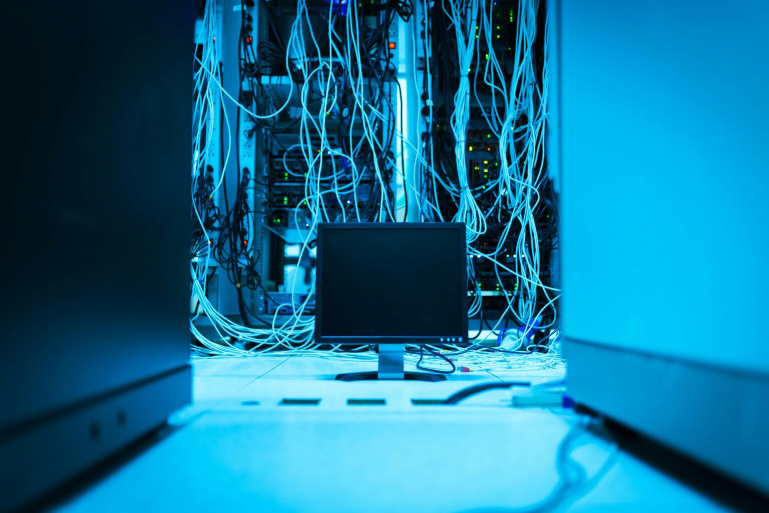Before — a server cabinet with tangled, undressed network cabling hanging loose in a data centre.